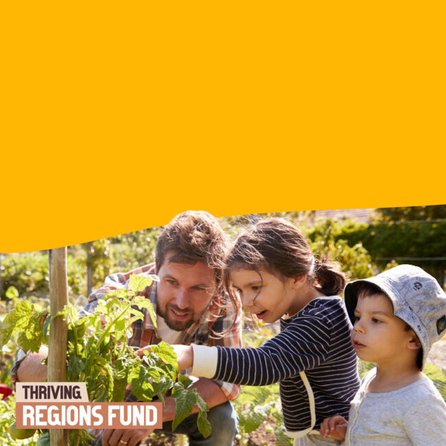 Thriving Regions Fund, an adult and two children in a garden tending to a plant.