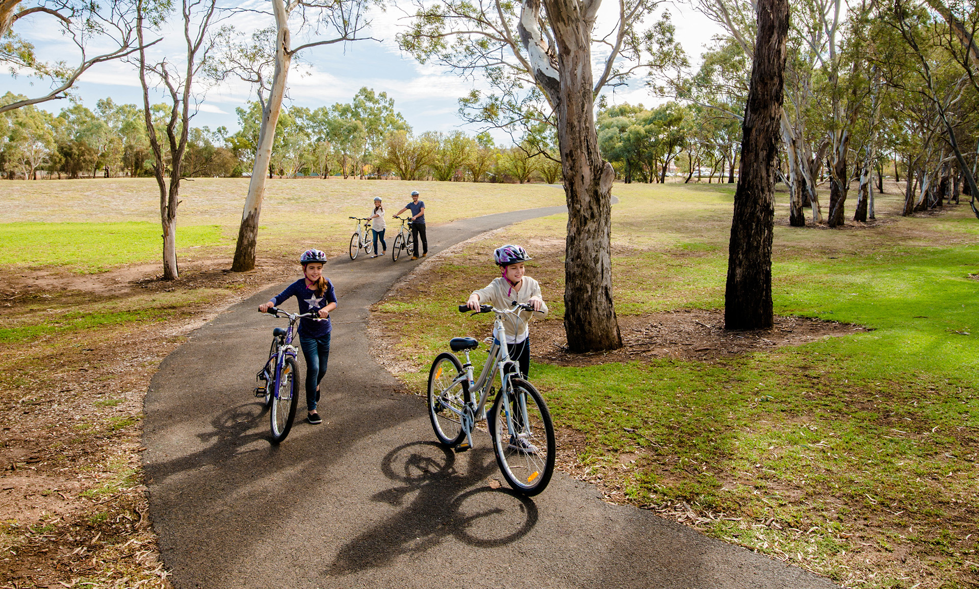 A family push bikes in a park