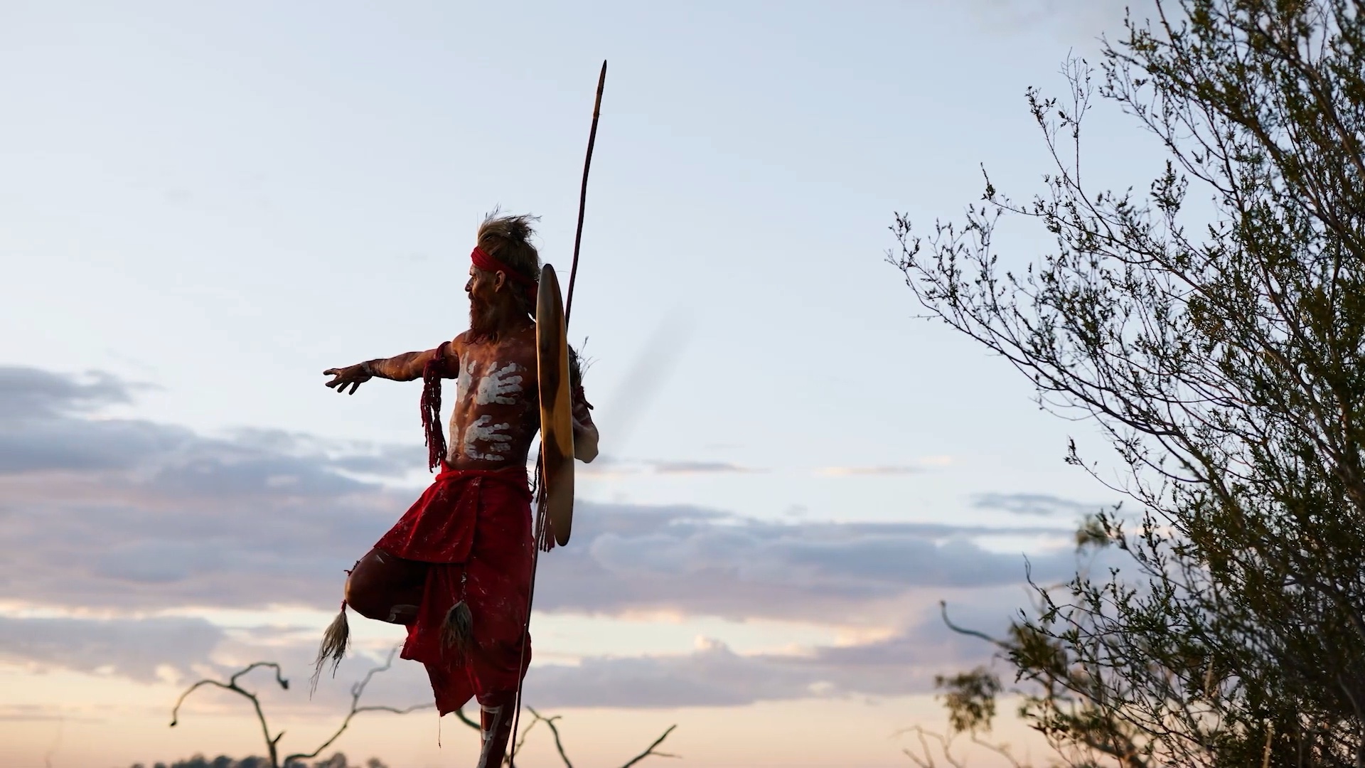 Yuandamarra holding a spear in First Nations traditional attire
