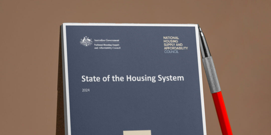 yLgxQnApaed State of the Housing System report with a pen lying against it on a brown background