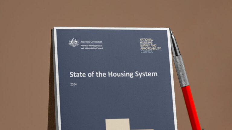 State of the Housing System report with a pen lying against it on a brown background