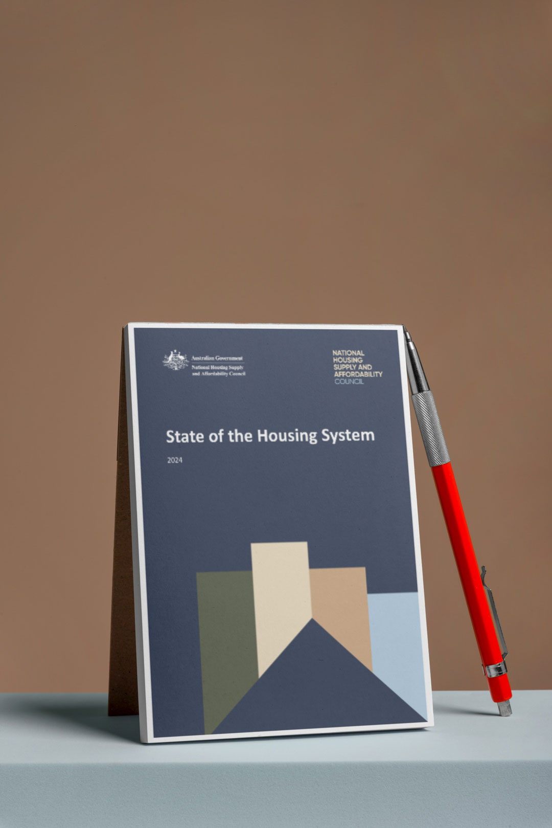 State of the Housing System report with a pen lying against it on a brown background