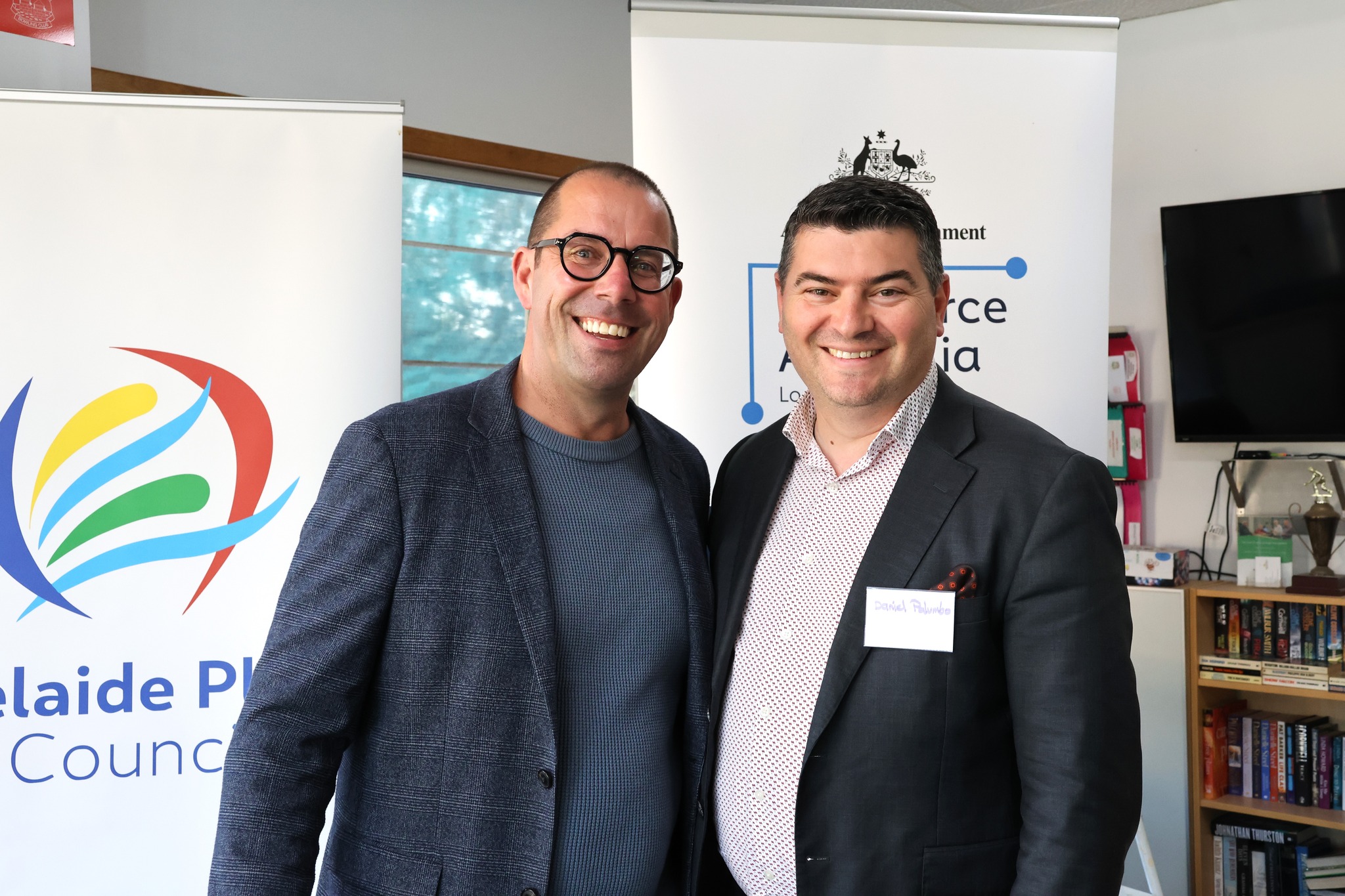 Two attendees smiling in front of event banners at the Live, Work and Thrive event.