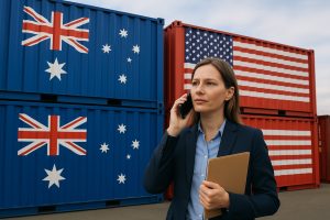 A person on the phone in front of two shipping containers with US and AUS flags.